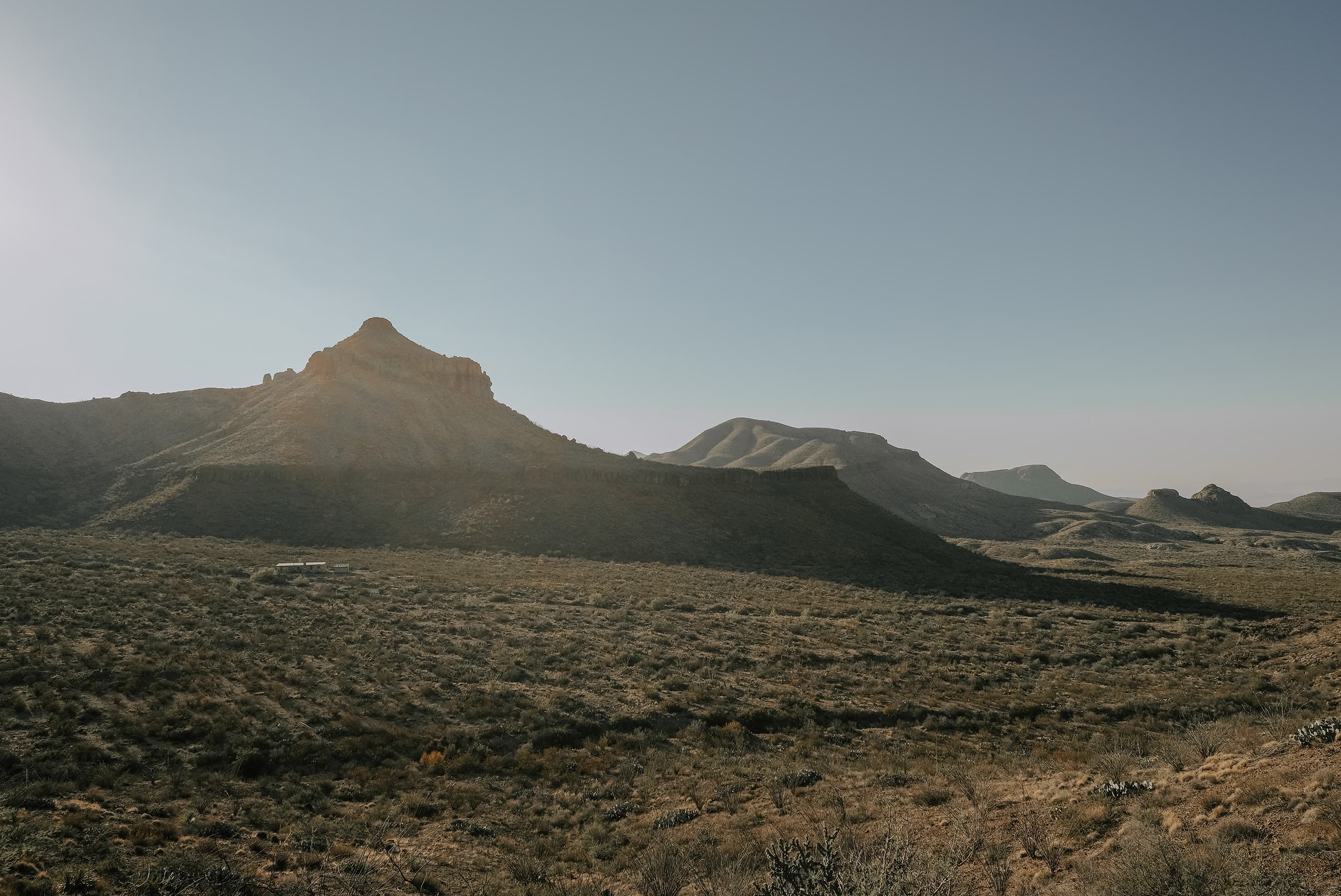 Low desert ridgelines going dark under a pale evening sky in far West Texas