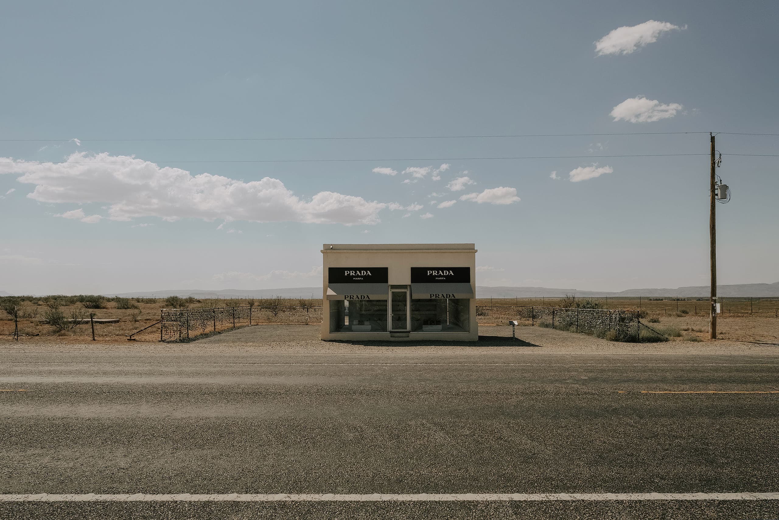Prada Marfa from across the highway, a power line running past it into open desert