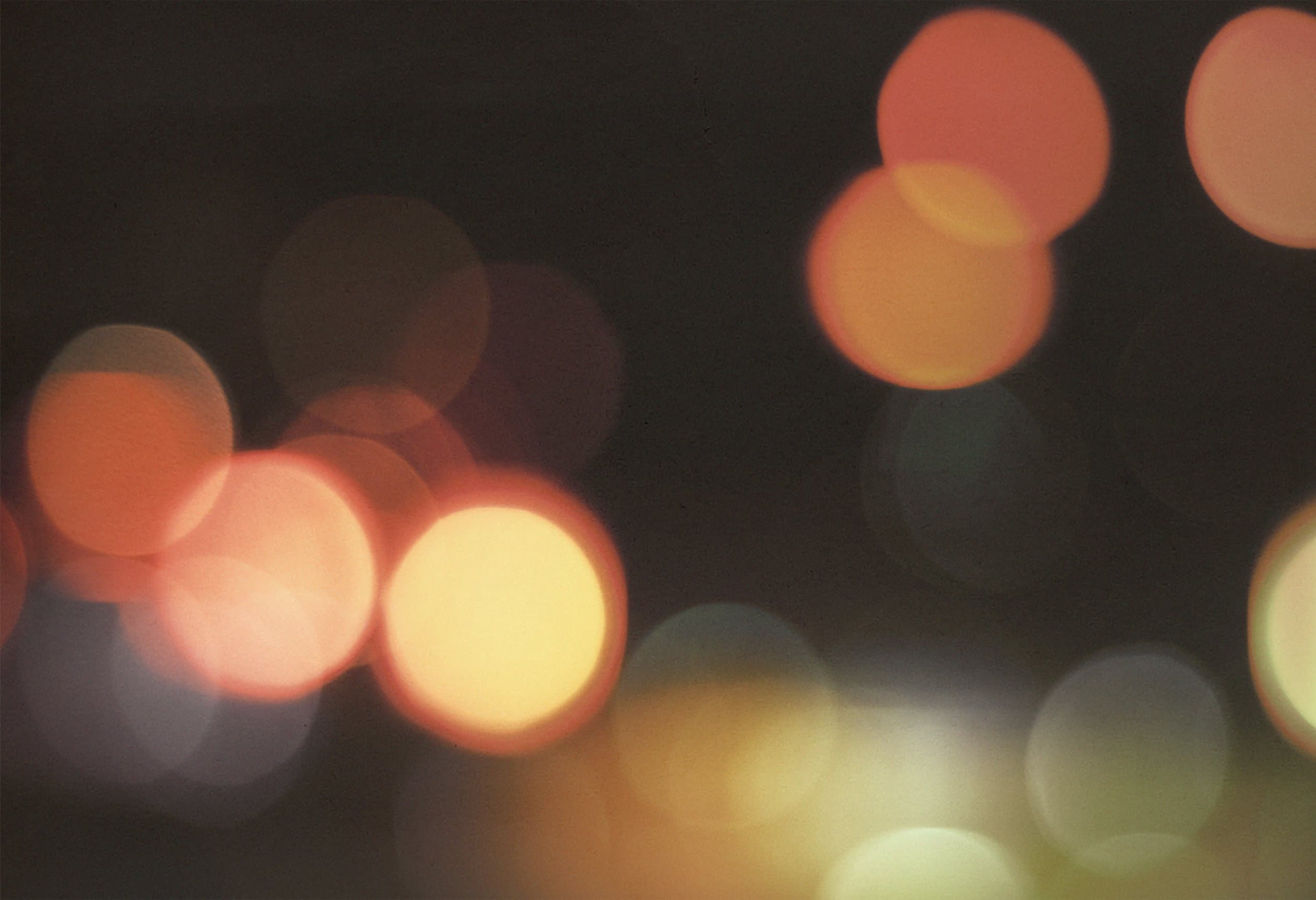 Bokeh lights source photograph, warm orange and pink defocused points of light against dark background