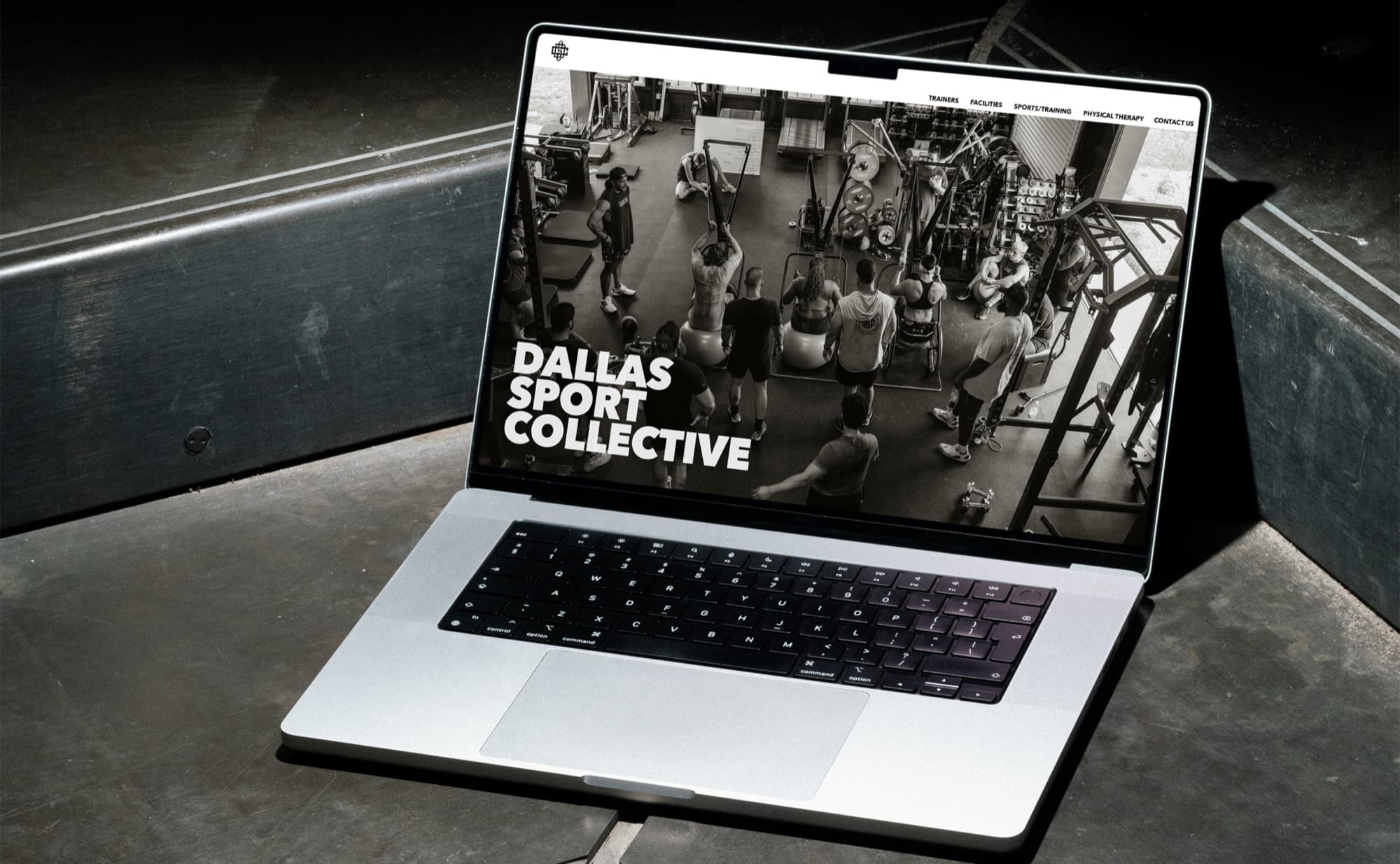 The Dallas Sport Collective marketing site open on a laptop, on concrete