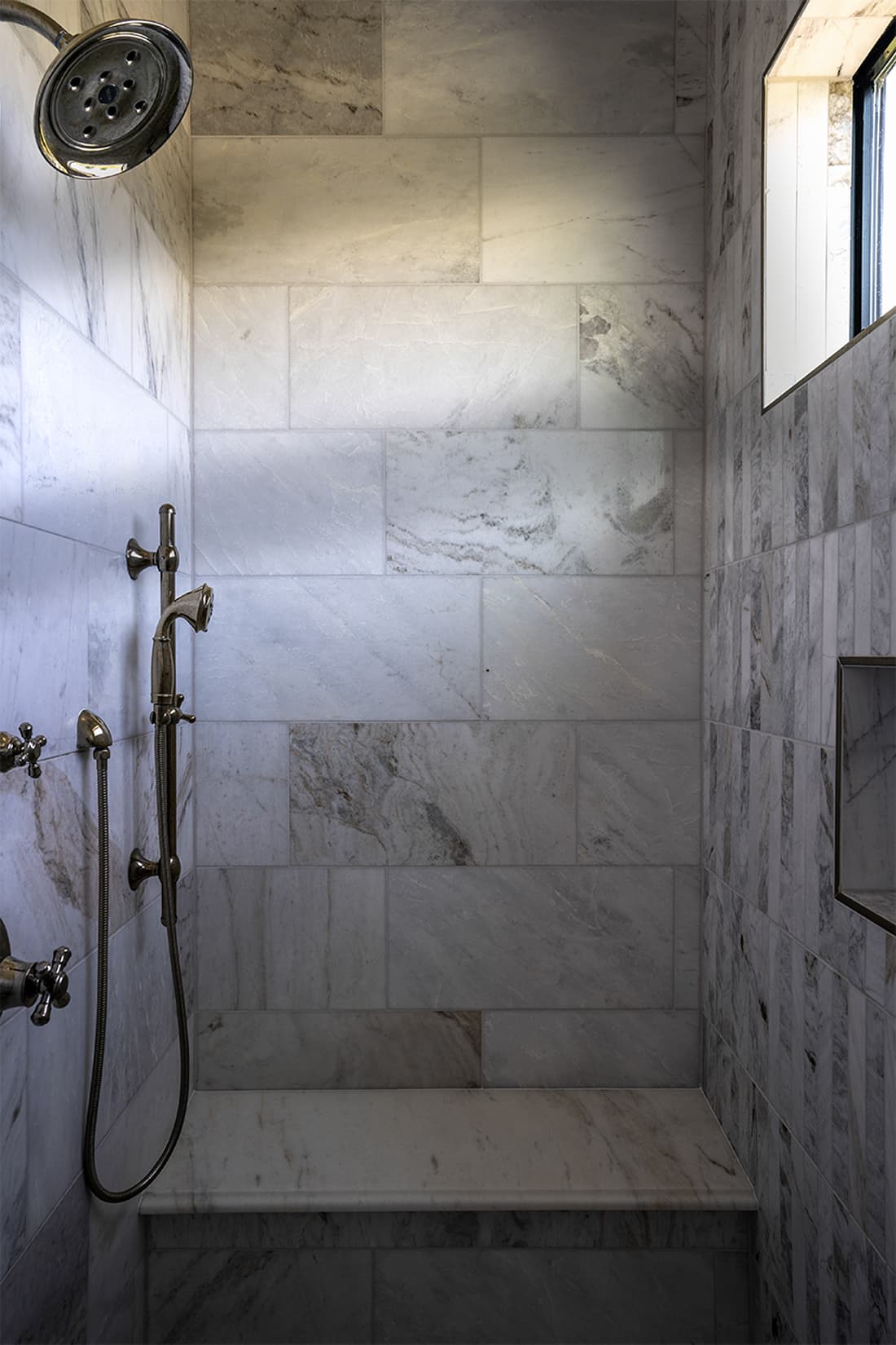 Urban southwest marble shower with horizontal running bond tile, handheld polished nickel fixture, and marble bench