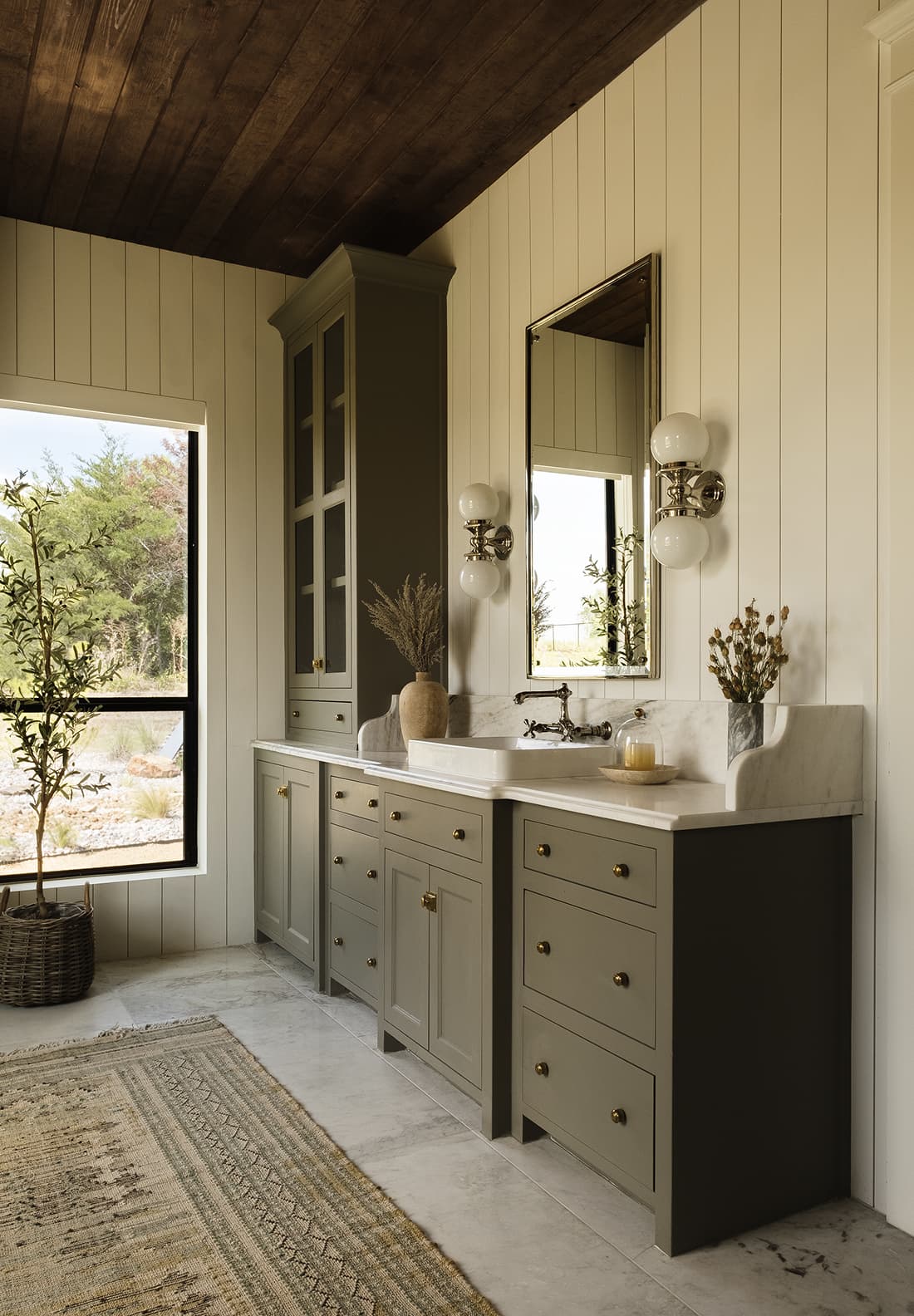 Her vanity wall, sage cabinetry with glass-front cabinet, double globe sconces, marble counter