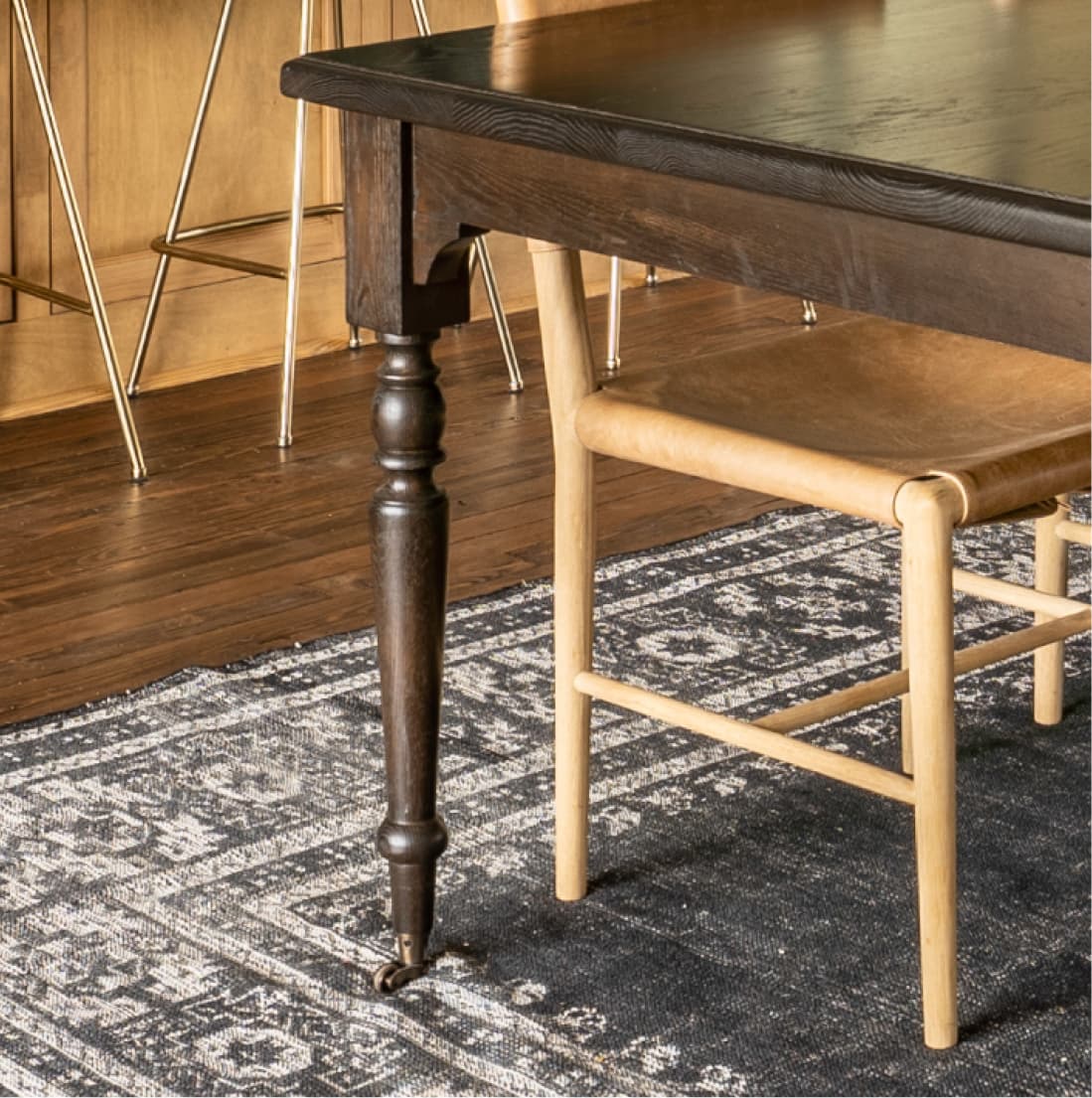 Dining table turned leg detail on dark patterned rug
