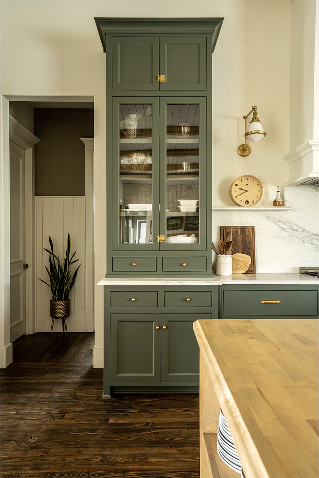 Glass-front cabinet with brass hardware, vintage clock, marble counter