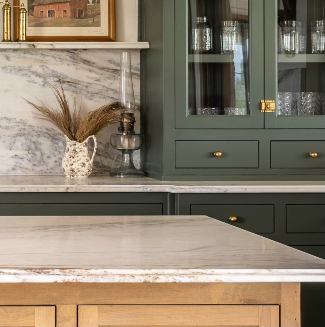 Marble counter vignette with dried arrangement, glass cabinet, brass hardware
