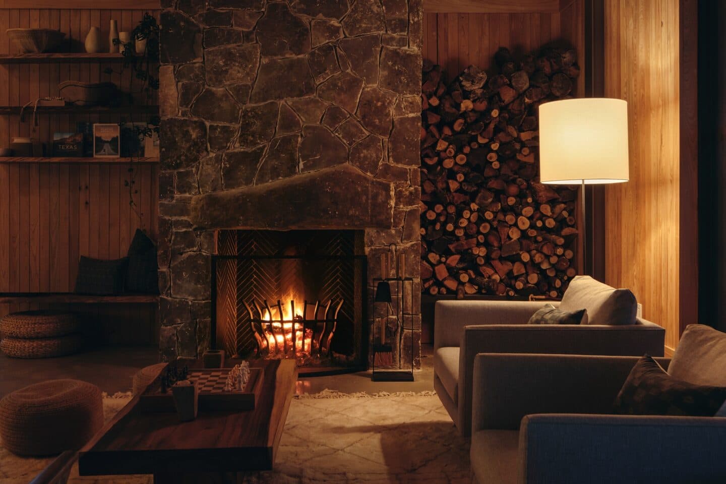 Walden Retreats living room with stone fireplace, stacked firewood, and chess board