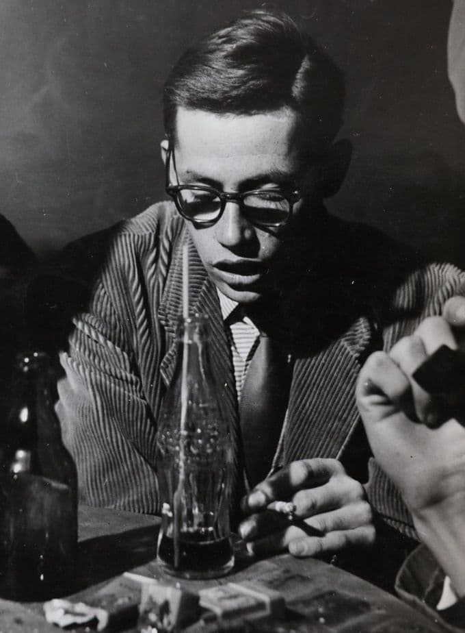 Black-and-white portrait, young man in glasses at a table with a Coca-Cola bottle
