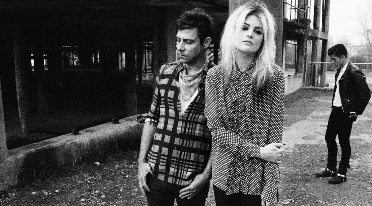 Black-and-white band portrait of two musicians in a derelict warehouse