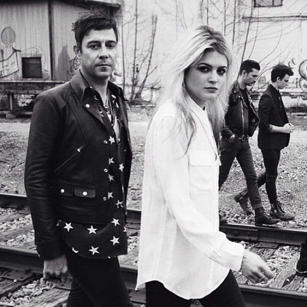 Black-and-white shot of band members walking along railroad tracks