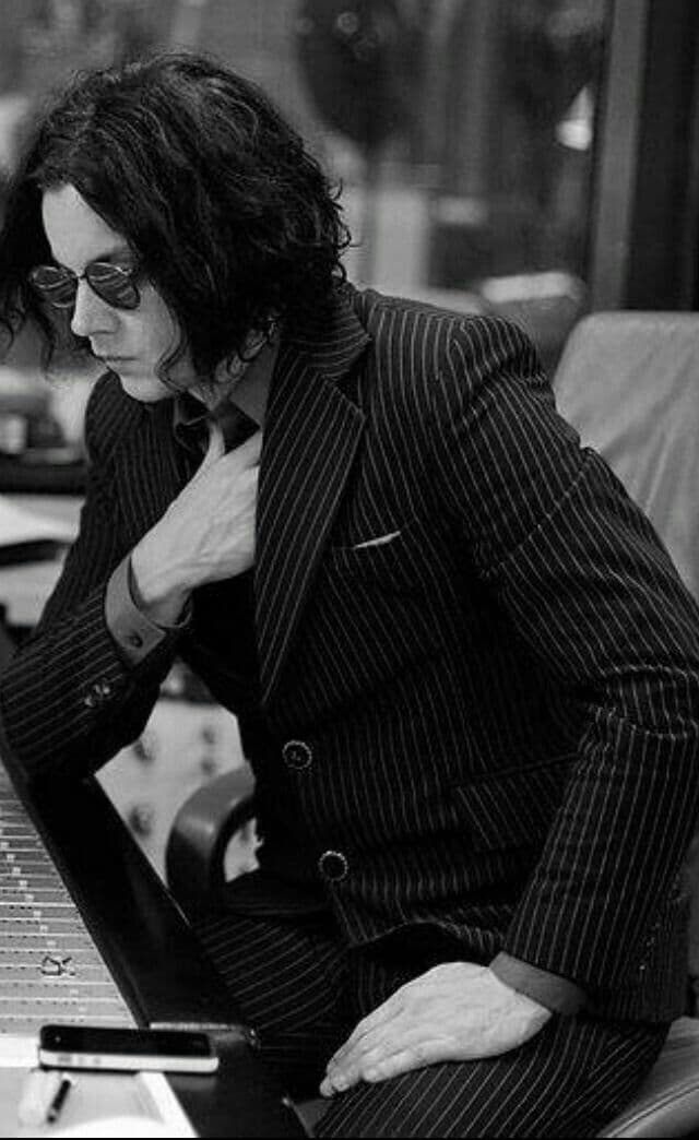 Black-and-white portrait, man in pinstripe suit and round glasses at a studio mixing desk