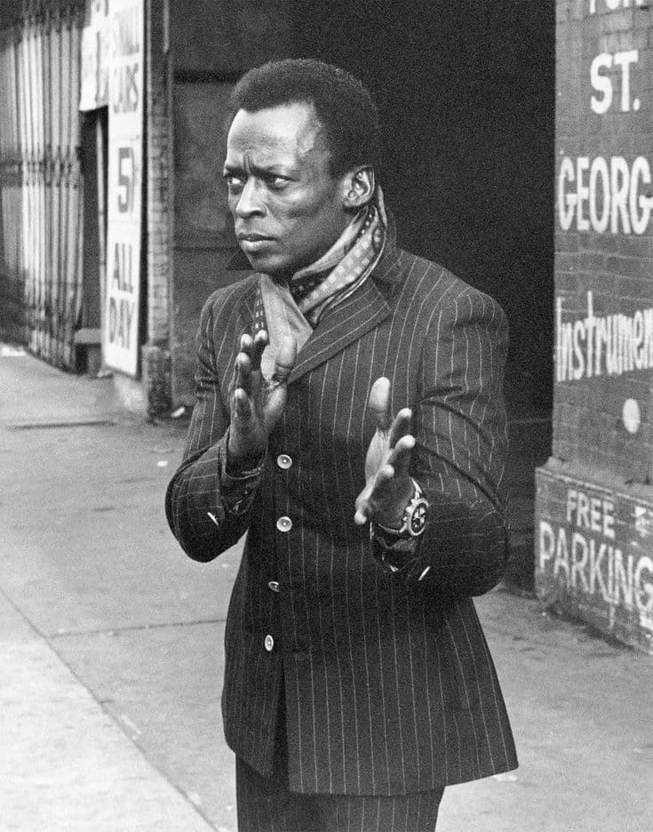 Black-and-white street portrait of Miles Davis in pinstripe suit on St. George Street