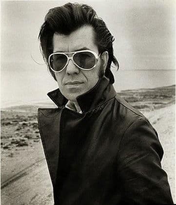 Black-and-white portrait, man in aviator sunglasses and leather jacket at the beach