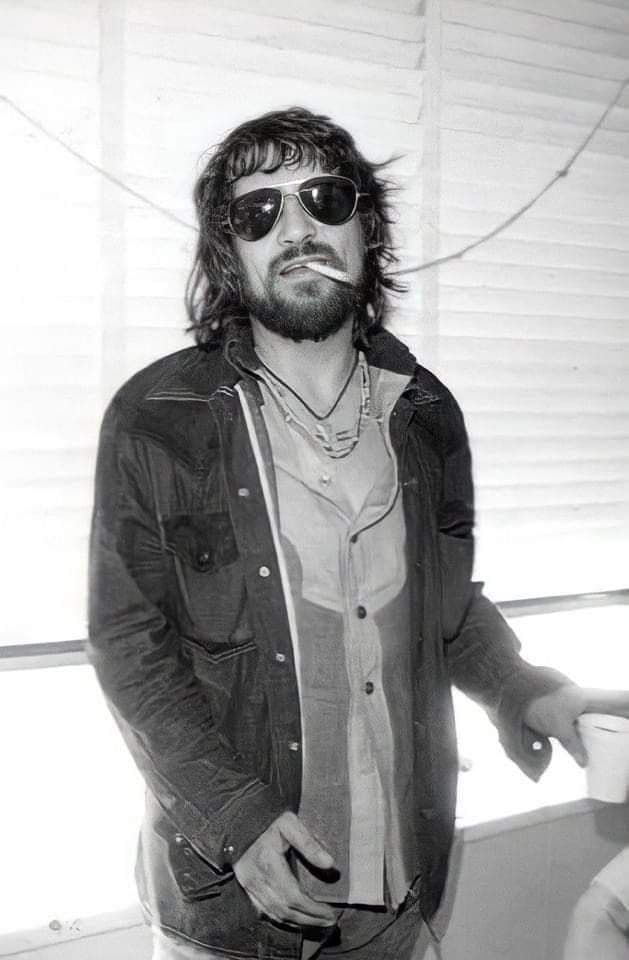 Black-and-white portrait of Waylon Jennings in aviator sunglasses with a cigarette