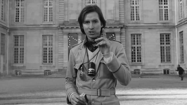 Black-and-white shot of Wes Anderson with camera in a Paris courtyard