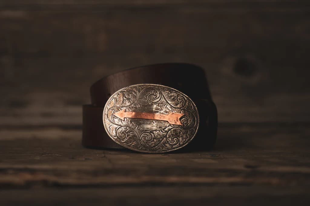 Engraved silver and copper belt buckle on a brown leather belt