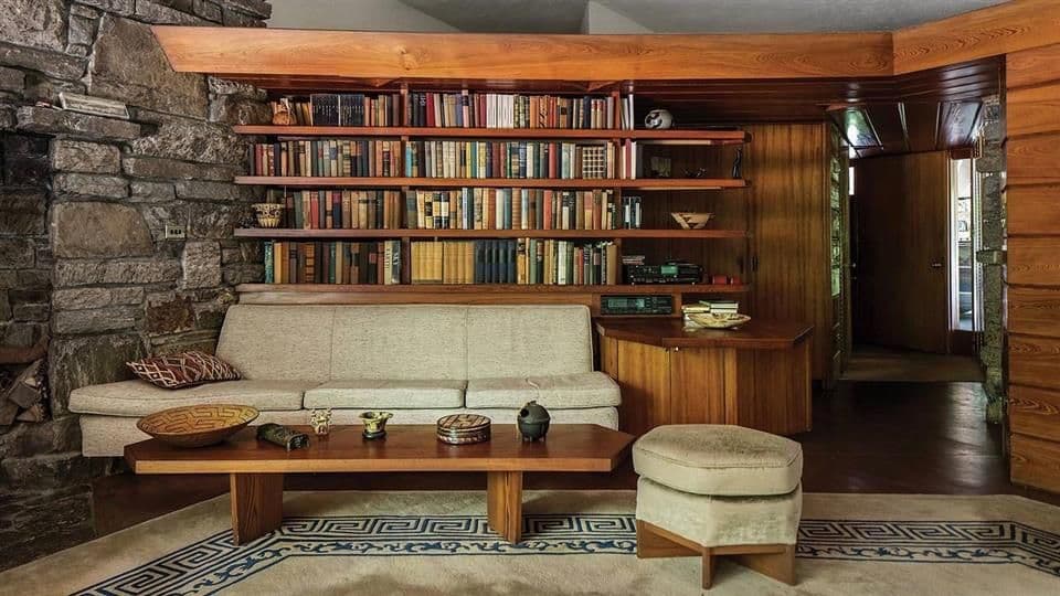 Frank Lloyd Wright Usonian living room with built-in bookshelves and stone fireplace