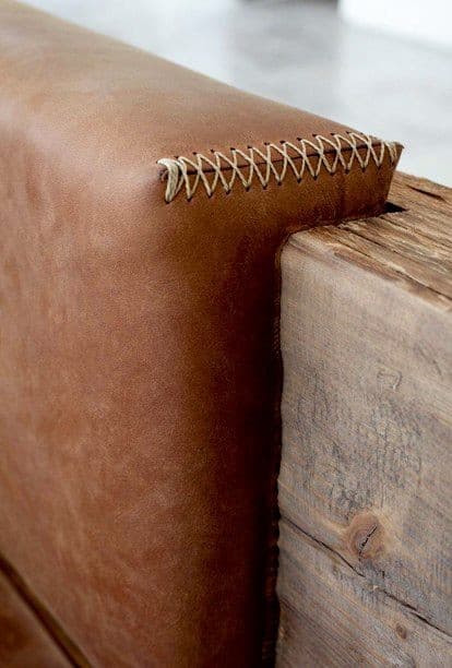 Tan leather bench corner with whip-stitched seam against a raw wood block