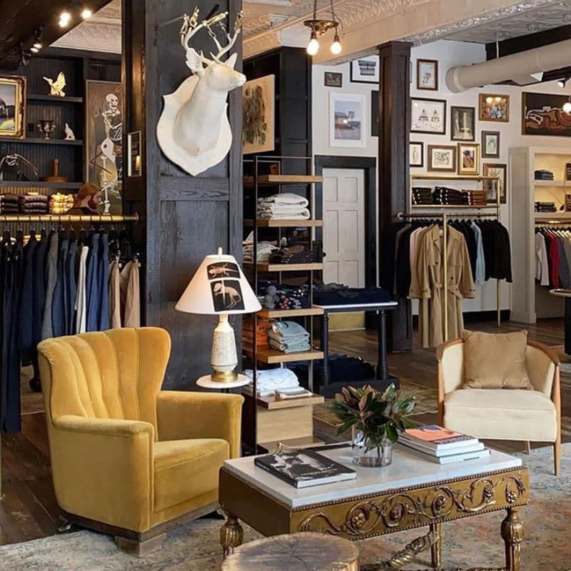 Eclectic menswear store interior with mounted deer head, mustard velvet chair, gallery wall