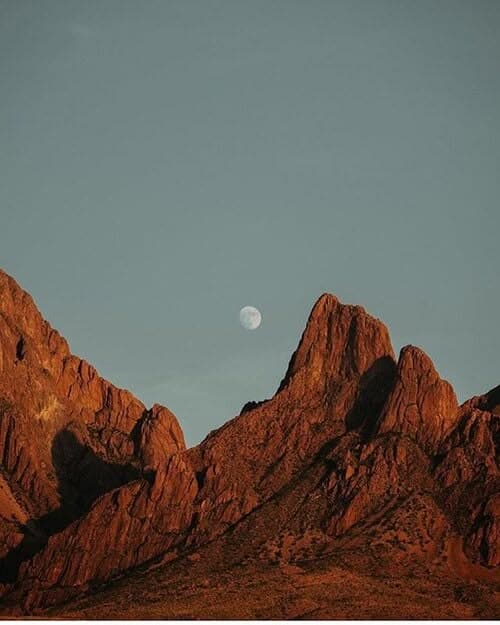 Organ Mountains glowing orange at sunset with the moon rising behind the peaks