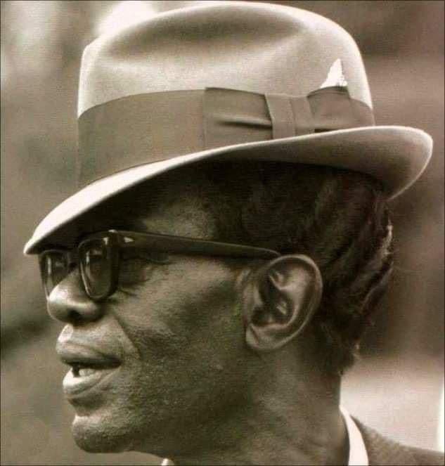 Black-and-white profile portrait, man in fedora and dark sunglasses