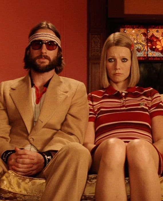 Royal Tenenbaums film still, two figures seated on a couch in a red-walled room