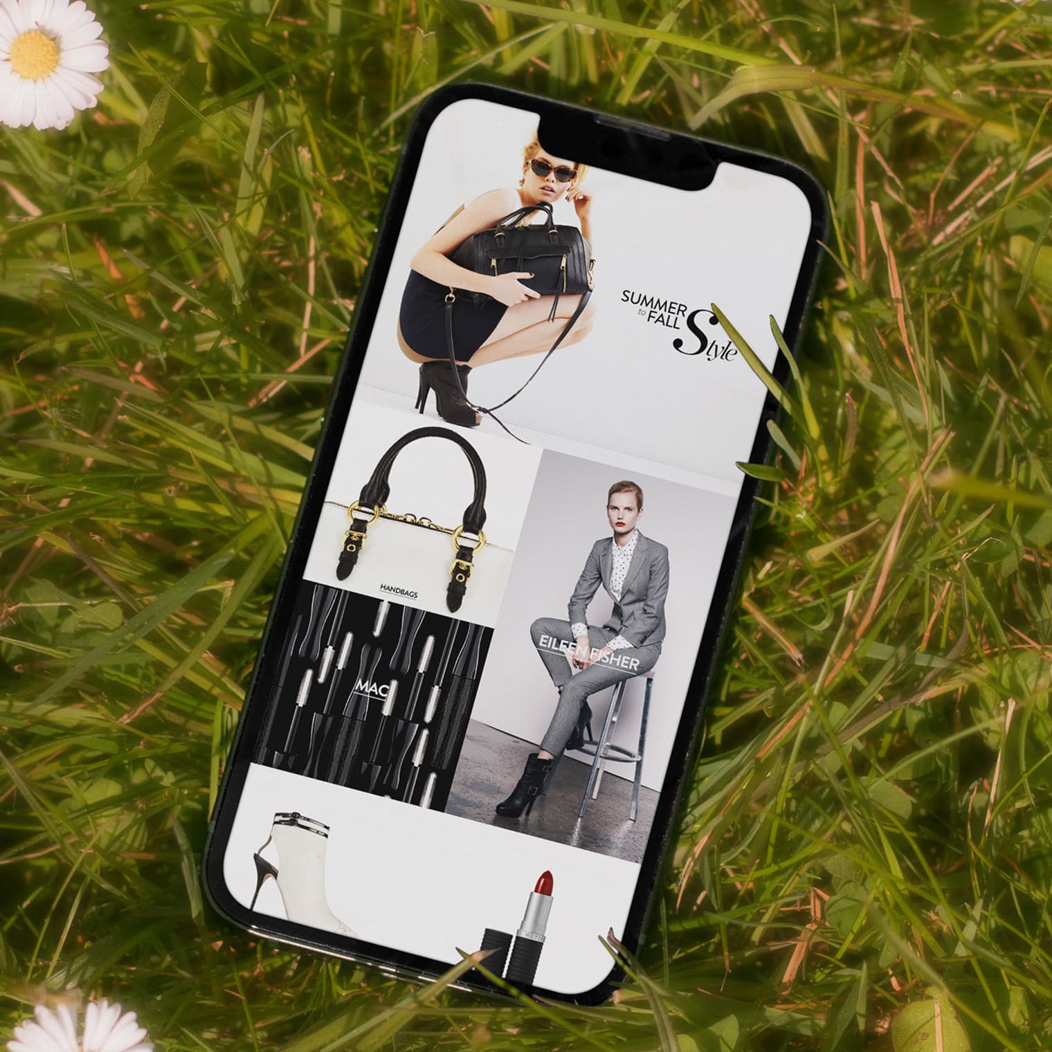 Nordstrom mobile homepage on iPhone laid in grass, showing Summer to Fall Style hero with handbag and blazer modules