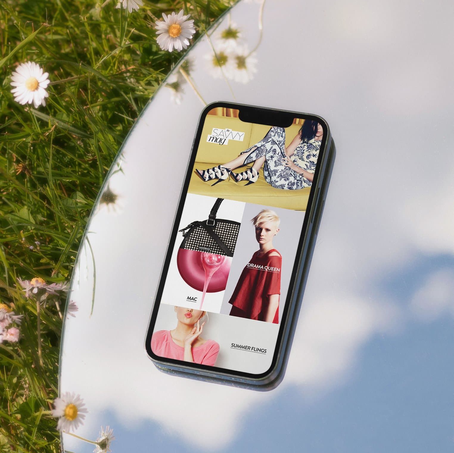 Nordstrom mobile homepage on iPhone laid on mirror reflecting clouds, showing Savvy Mag editorial with Drama Queen and Mac modules