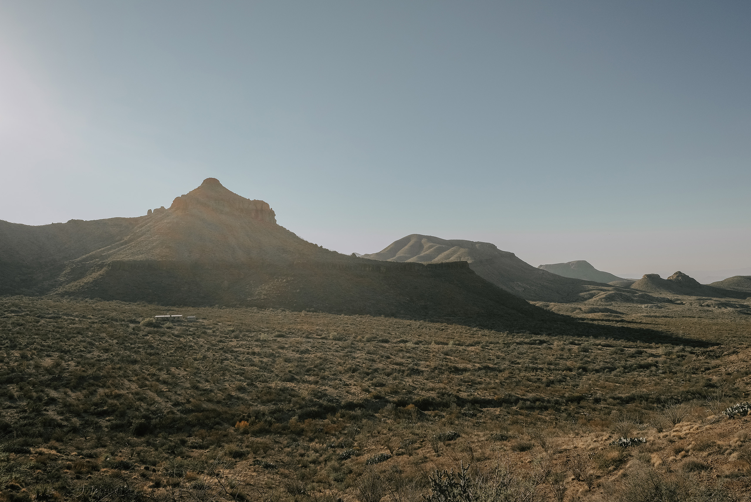 Low desert ridgelines going dark under a pale evening sky in far West Texas