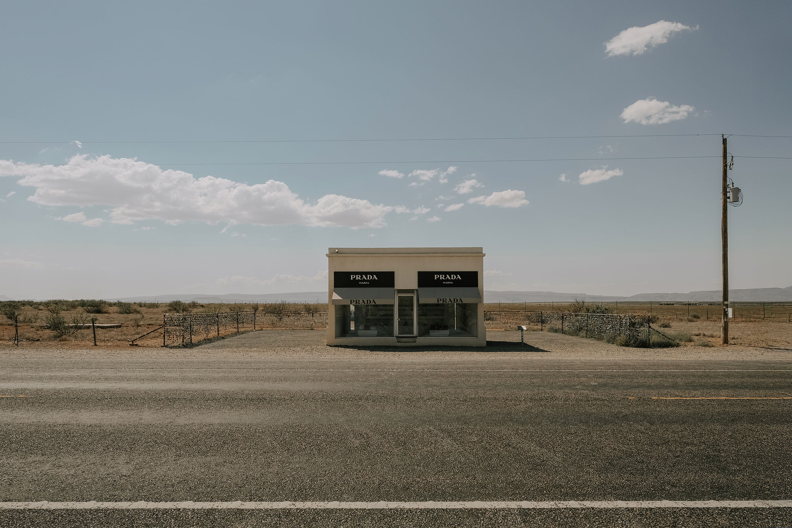 Prada Marfa from across the highway, a power line running past it into open desert