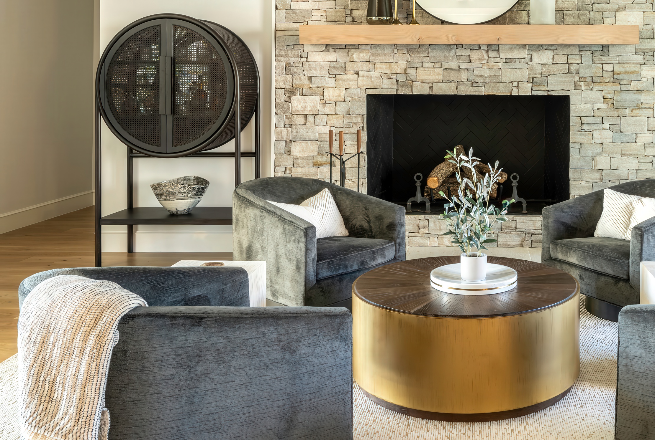 Front view of the conversation grouping with the round black bar cabinet on the left, two swivels around the brass coffee table, fireplace beyond