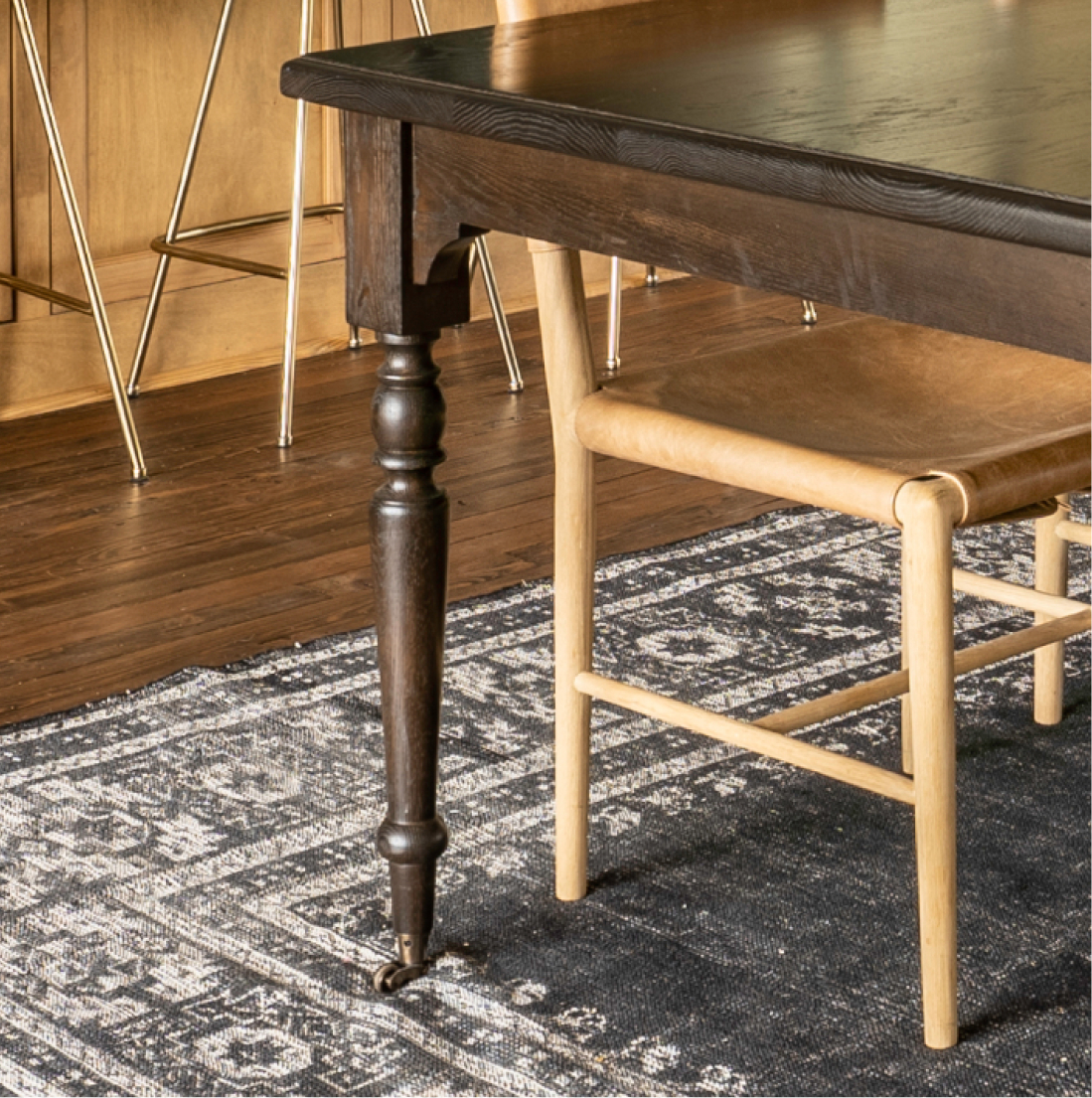 Dining table turned leg detail on dark patterned rug