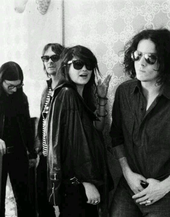 Black-and-white band portrait, four musicians against patterned wallpaper