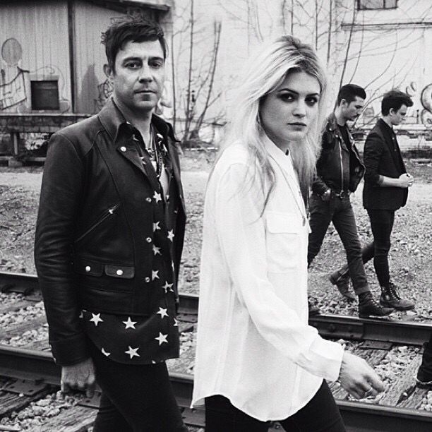 Black-and-white shot of band members walking along railroad tracks