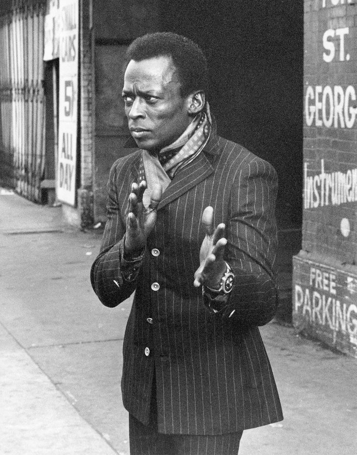 Black-and-white street portrait of Miles Davis in pinstripe suit on St. George Street