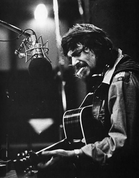 Black-and-white musician at studio microphone with acoustic guitar