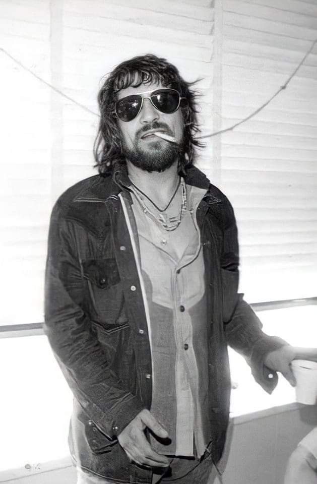 Black-and-white portrait of Waylon Jennings in aviator sunglasses with a cigarette
