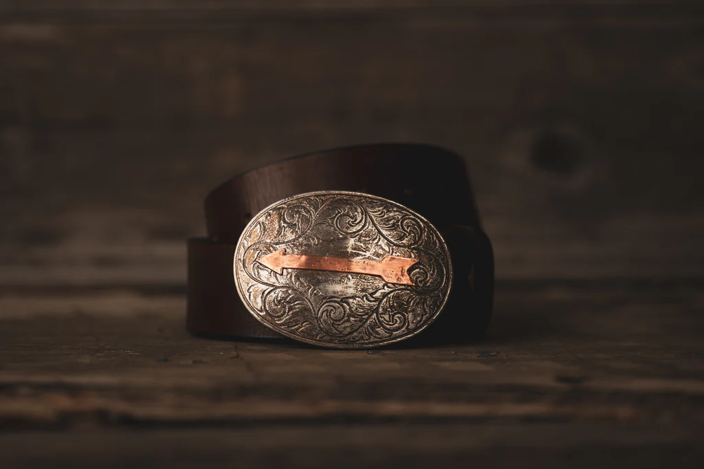 Engraved silver and copper belt buckle on a brown leather belt