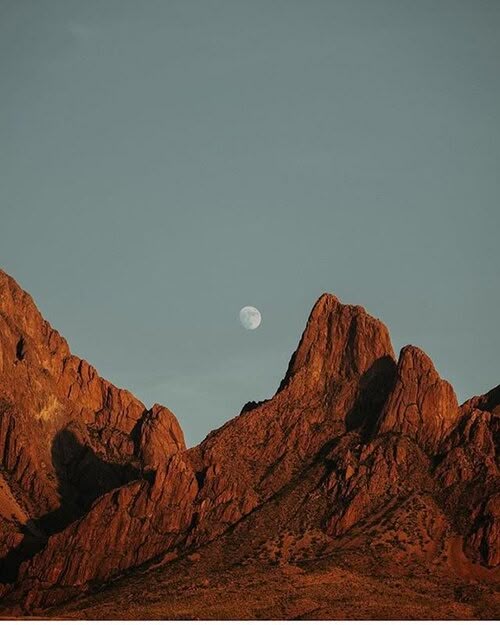 Organ Mountains glowing orange at sunset with the moon rising behind the peaks
