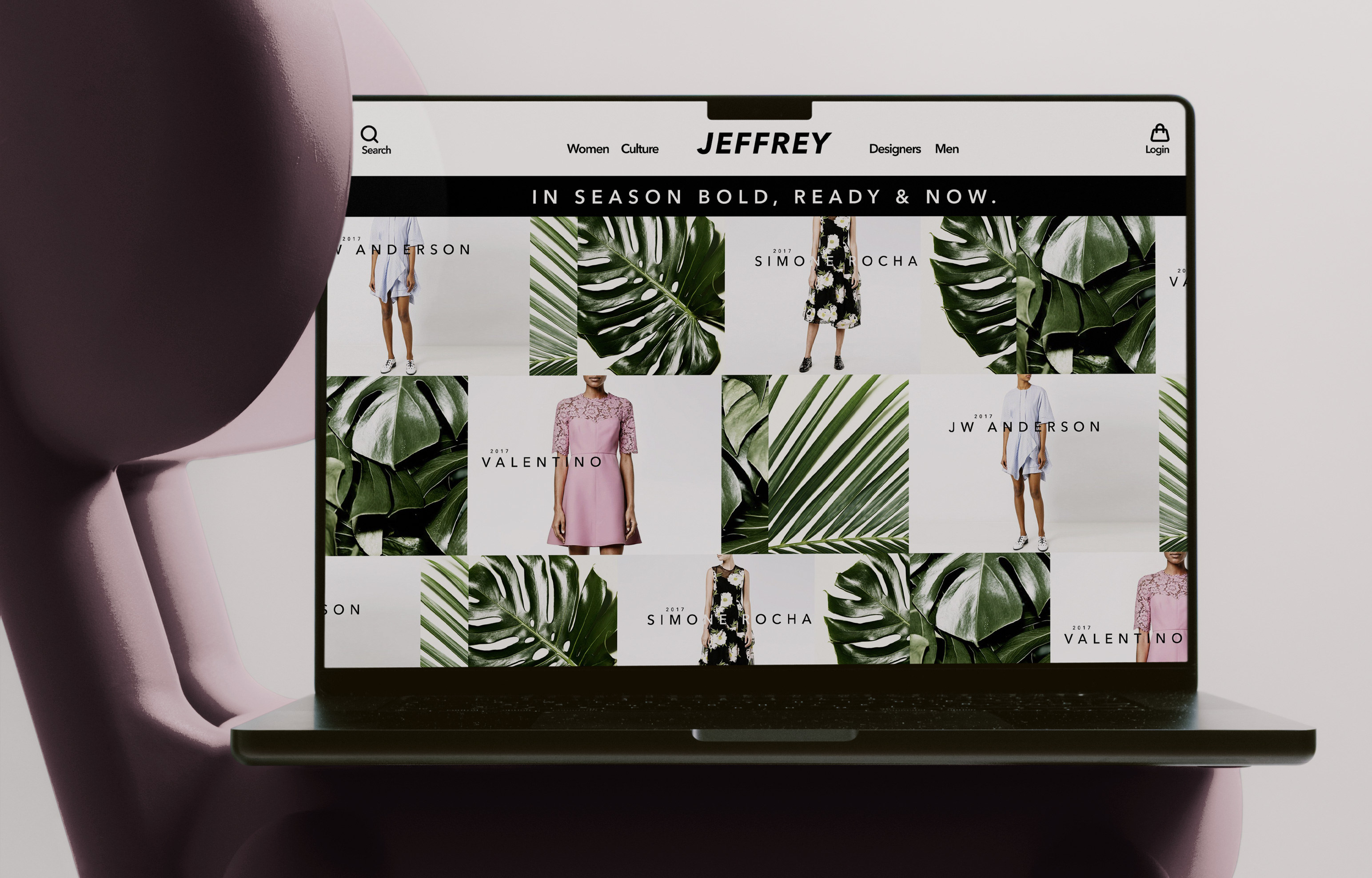 The Jeffrey homepage open on a laptop resting on a pink moulded chair, the IN SEASON BOLD, READY & NOW banner above the campaign grid of dresses and monstera leaves