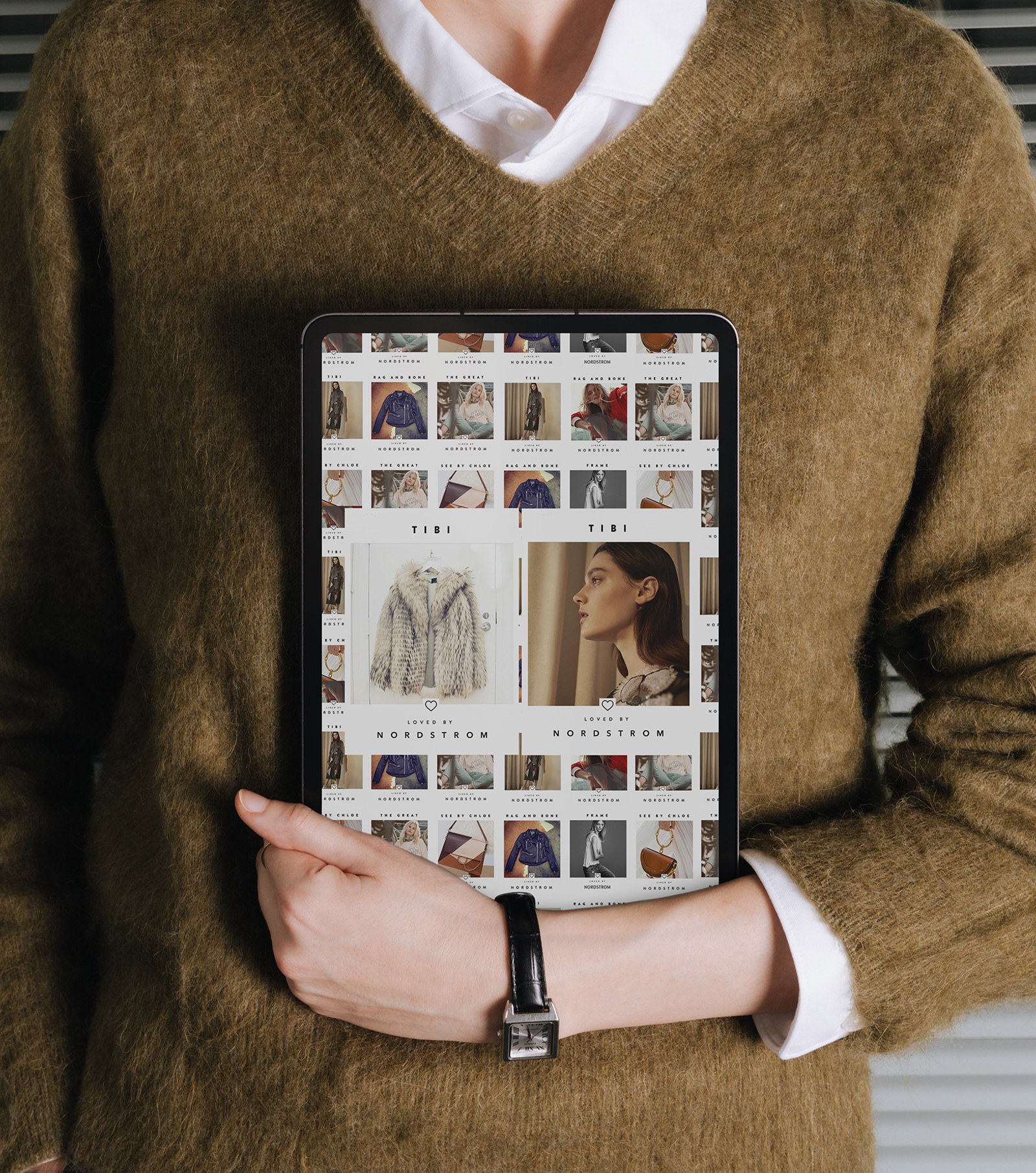A person in a mohair sweater holding a tablet showing the Loved by Nordstrom wall, the two large TIBI tiles at its centre